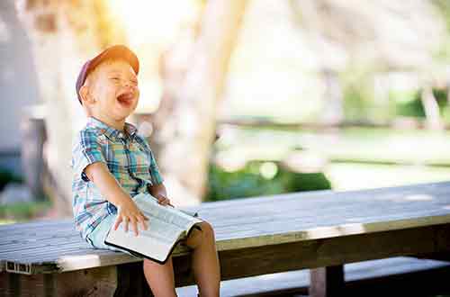 Happy little boy reading a book